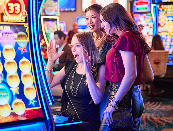 Three women playing slots at a machine in the casino